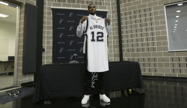 LaMarcus Aldridge poses with his new jersey following a news conference at the team's practice facility where he was formally introduced after he signed with the San Antonio Spurs NBA basketball team, Friday, July 10, 2015, in San Antonio. (AP Photo/Eric Gay)